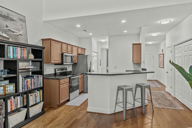 310 Lockerbie Ct Unit 1057, Myrtle Beach, SC 29577 - kitchen with appliances with stainless steel finishes, dark countertops, light wood-style floors, a breakfast bar area, and recessed lighting