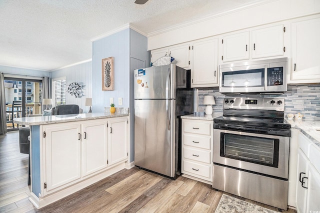 5601 N Ocean Blvd Unit E-113, Myrtle Beach, SC 29577 - kitchen featuring appliances with stainless steel finishes, crown molding, a peninsula, backsplash, and light wood-type flooring