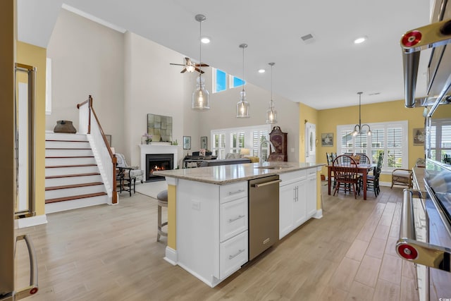 932 Abernathy Pl, Surfside Beach, SC 29575 - kitchen with stainless steel dishwasher, a warm lit fireplace, healthy amount of natural light, light wood-type flooring, and recessed lighting