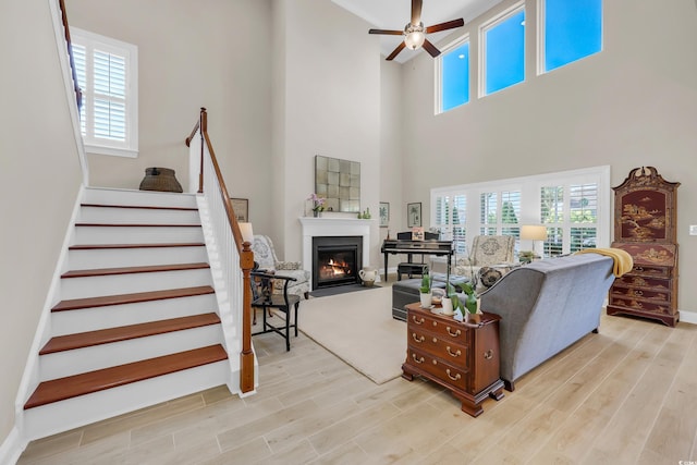932 Abernathy Pl, Surfside Beach, SC 29575 - living room with a glass covered fireplace, ceiling fan, healthy amount of natural light, stairway, and a towering ceiling