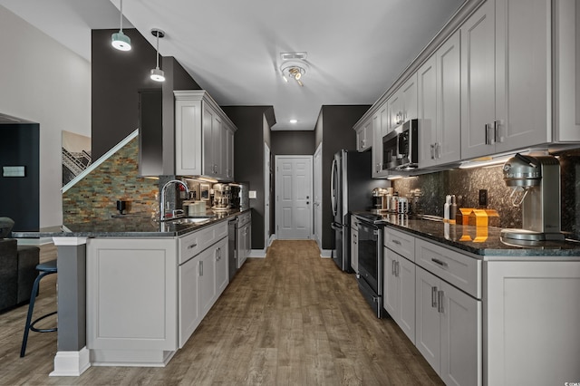 752 Hobonny Loop, Longs, SC 29568 - kitchen with stainless steel appliances, a breakfast bar area, tasteful backsplash, wood finished floors, and dark stone counters