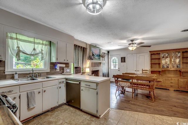 4189 Schoolhouse Cir, Little River, SC 29566 - kitchen with dishwasher, a ceiling fan, a peninsula, a textured ceiling, and a fireplace
