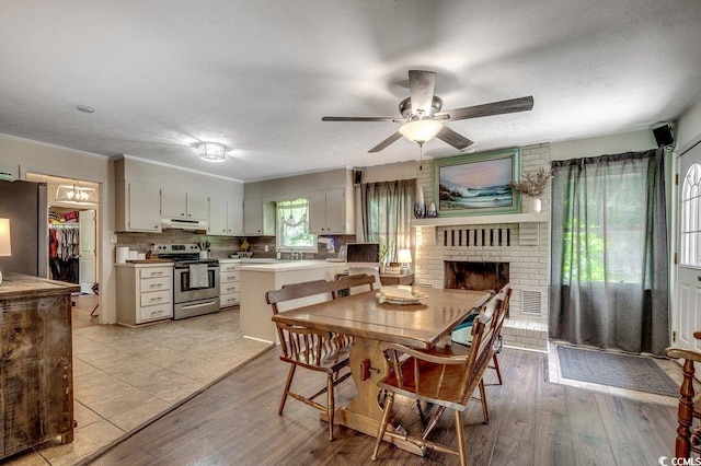 4189 Schoolhouse Cir, Little River, SC 29566 - dining space with a ceiling fan, a brick fireplace, and light wood-type flooring
