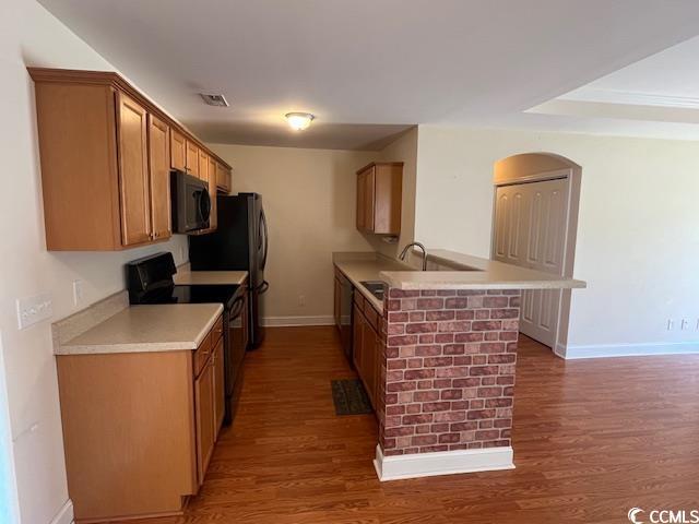 298 Weyburn St, Myrtle Beach, SC 29579 - kitchen featuring black appliances, a peninsula, wood finished floors, light countertops, and brown cabinetry