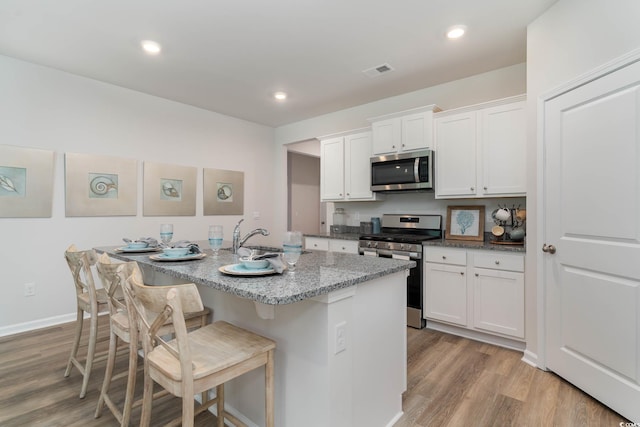 1402 Nokota Dr, Conway, SC 29526 - kitchen featuring stainless steel appliances, light wood finished floors, white cabinets, a kitchen bar, and recessed lighting