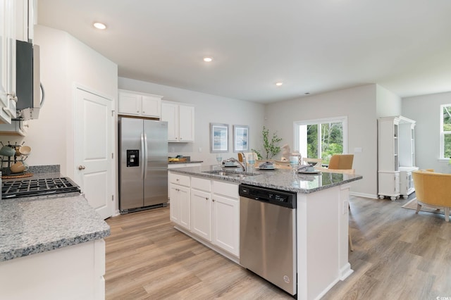 1402 Nokota Dr, Conway, SC 29526 - kitchen with stainless steel appliances, light wood-style flooring, a center island with sink, white cabinets, and light stone counters