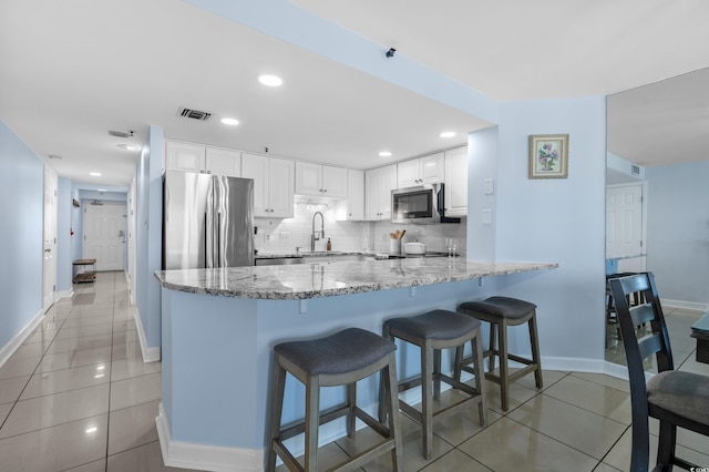 5511 N Ocean Blvd Unit 1801, Myrtle Beach, SC 29577 - kitchen with appliances with stainless steel finishes, light stone countertops, a peninsula, light tile patterned floors, and white cabinetry