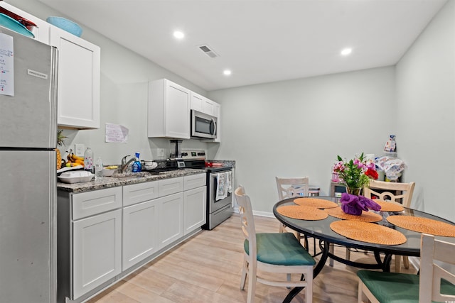 304 1st Ave N, Myrtle Beach, SC 29577 - kitchen with stainless steel appliances, light wood finished floors, recessed lighting, white cabinetry, and light stone counters