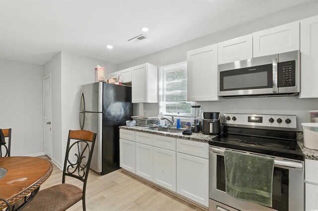 304 1st Ave N, Myrtle Beach, SC 29577 - kitchen featuring appliances with stainless steel finishes, white cabinetry, light wood-type flooring, light stone countertops, and recessed lighting