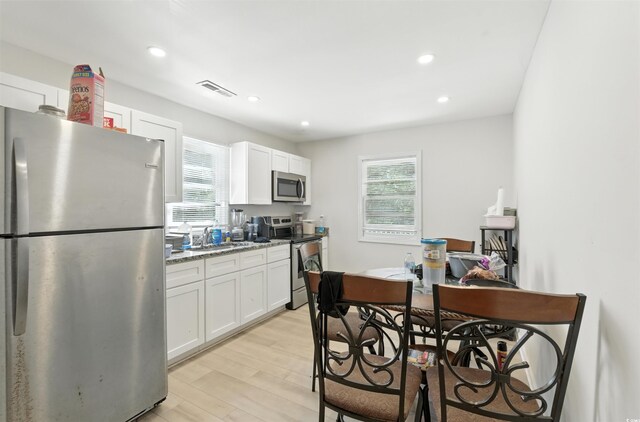 304 1st Ave N, Myrtle Beach, SC 29577 - kitchen with appliances with stainless steel finishes, white cabinets, light wood-type flooring, light stone countertops, and recessed lighting
