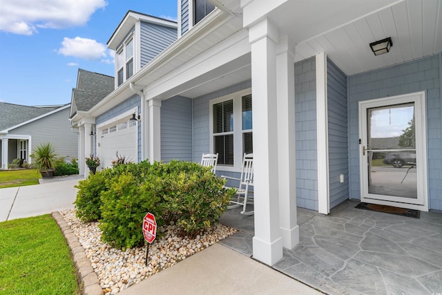 413 Goldenrod Cir Unit 2B, Little River, SC 29566 - view of exterior entry with a porch, a shingled roof, driveway, and an attached garage