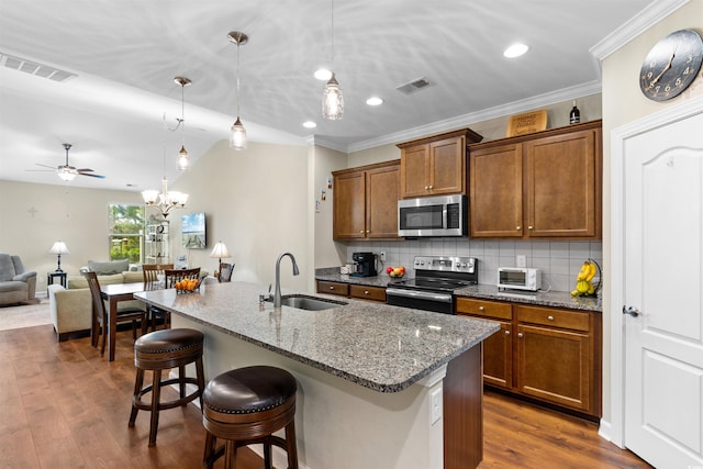 413 Goldenrod Cir Unit 2B, Little River, SC 29566 - kitchen featuring appliances with stainless steel finishes, brown cabinets, a breakfast bar, open floor plan, and light stone countertops