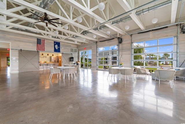 413 Goldenrod Cir Unit 2B, Little River, SC 29566 - misc room with high vaulted ceiling, concrete floors, a barn door, and wood walls