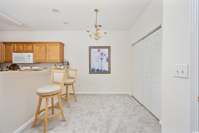 155 Chenoa Dr Unit E, Murrells Inlet, SC 29576 - kitchen featuring white microwave, light carpet, a chandelier, a kitchen breakfast bar, and decorative light fixtures