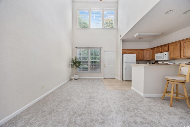 155 Chenoa Dr Unit E, Murrells Inlet, SC 29576 - kitchen with white appliances, plenty of natural light, light colored carpet, brown cabinetry, and a high ceiling