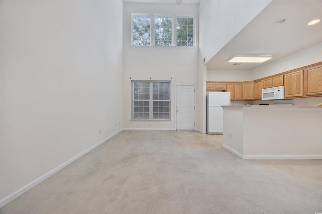 155 Chenoa Dr Unit D, Murrells Inlet, SC 29576 - kitchen featuring white appliances, light colored carpet, light countertops, a towering ceiling, and a peninsula