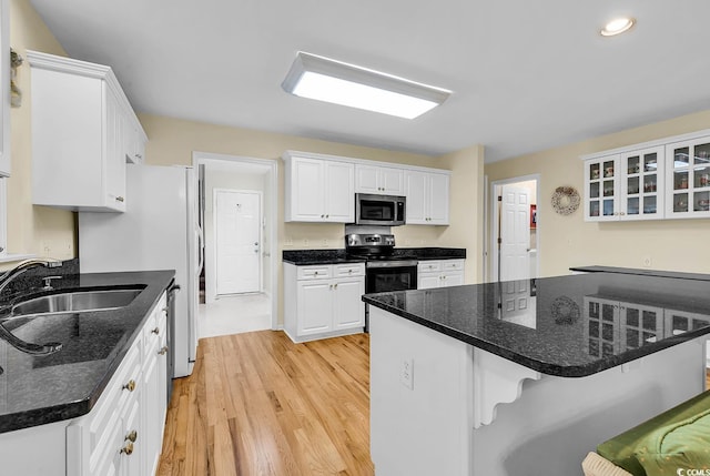 241 Black Duck Rd, Pawleys Island, SC 29585 - kitchen featuring appliances with stainless steel finishes, a breakfast bar, light wood-style flooring, white cabinets, and glass insert cabinets