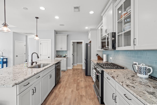 277 Splendor Cir, Murrells Inlet, SC 29576 - kitchen with stainless steel appliances, decorative backsplash, light wood finished floors, white cabinetry, and decorative light fixtures