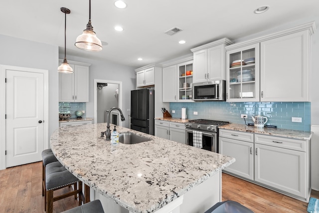 277 Splendor Cir, Murrells Inlet, SC 29576 - kitchen featuring appliances with stainless steel finishes, a breakfast bar area, backsplash, glass insert cabinets, and hanging light fixtures