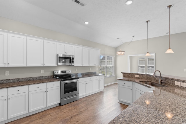 347 Leste Rd, Myrtle Beach, SC 29588 - kitchen with stainless steel appliances, vaulted ceiling, wood finished floors, white cabinetry, and decorative light fixtures