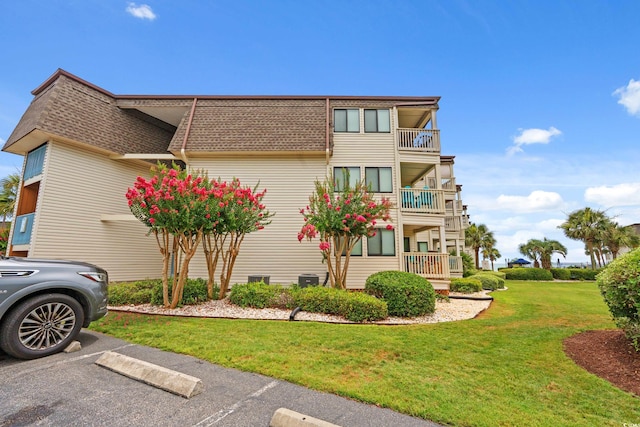5601 N Ocean Blvd Unit B-314, Myrtle Beach, SC 29577 - view of property exterior with a shingled roof, mansard roof, a yard, a balcony, and uncovered parking