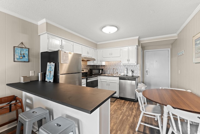 5601 N Ocean Blvd Unit B-314, Myrtle Beach, SC 29577 - kitchen featuring stainless steel appliances, dark countertops, under cabinet range hood, a peninsula, and crown molding