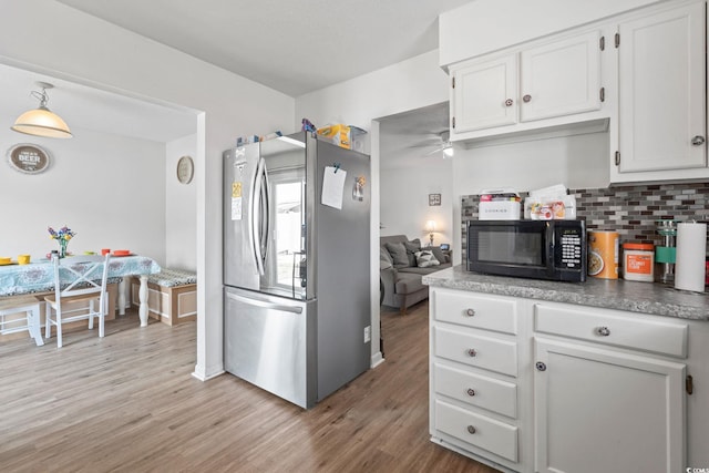 1311 Turkey Ridge Rd Unit A, Surfside Beach, SC 29575 - kitchen with freestanding refrigerator, black microwave, light wood-style floors, white cabinets, and decorative backsplash