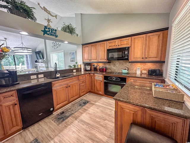 145 Hartland Dr Unit 4-E, Myrtle Beach, SC 29572 - kitchen featuring black appliances, a textured ceiling, brown cabinets, light wood-style flooring, and dark stone countertops