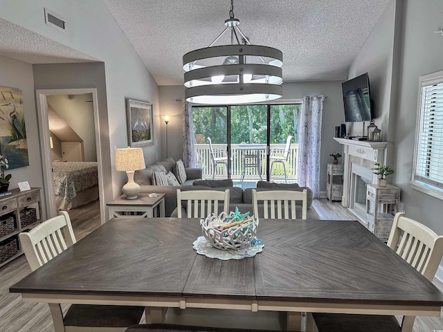 145 Hartland Dr Unit 4-E, Myrtle Beach, SC 29572 - dining area with vaulted ceiling, a textured ceiling, wood finished floors, and a glass covered fireplace
