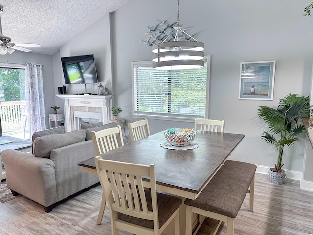145 Hartland Dr Unit 4-E, Myrtle Beach, SC 29572 - dining area featuring a textured ceiling, light wood-style floors, a tile fireplace, ceiling fan, and lofted ceiling