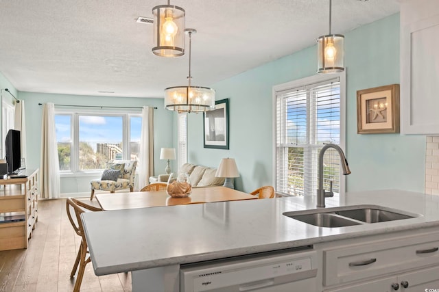 4105 S Ocean Blvd Unit 102, North Myrtle Beach, SC 29582 - kitchen with dishwasher, a textured ceiling, open floor plan, light wood-style floors, and hanging light fixtures