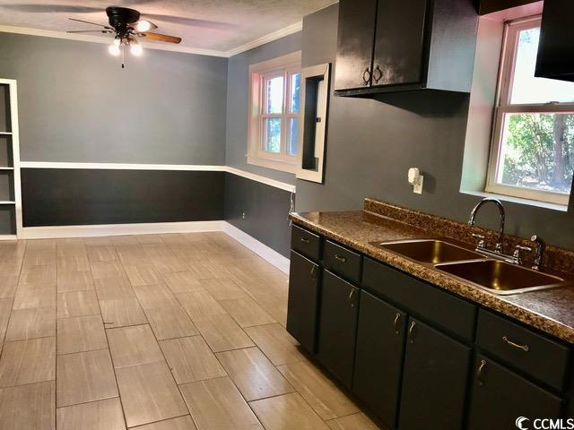 3110 Pinewood Dr, Loris, SC 29569 - kitchen with ornamental molding, healthy amount of natural light, a ceiling fan, dark countertops, and dark cabinets