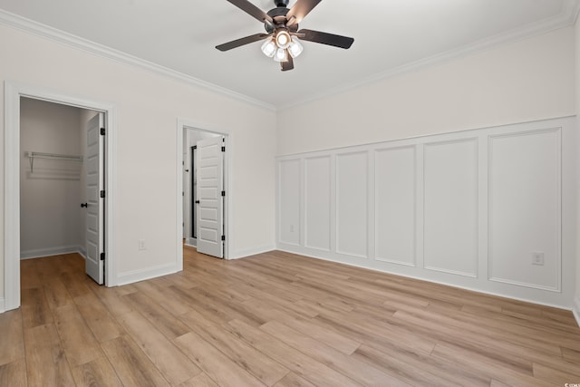 1718 26th Ave N, North Myrtle Beach, SC 29582 - unfurnished bedroom featuring crown molding, light wood-style flooring, a decorative wall, a spacious closet, and a ceiling fan