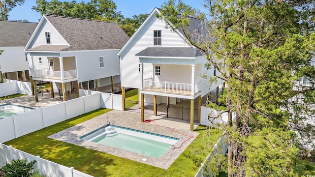 1718 26th Ave N, North Myrtle Beach, SC 29582 - back of property with a balcony, roof with shingles, a fenced backyard, and a patio