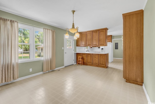 823 Bellamy Ave, Murrells Inlet, SC 29576 - kitchen with brown cabinetry, light flooring, light countertops, hanging light fixtures, and white fridge with ice dispenser