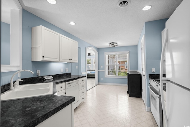4162 Dupree Dr, Little River, SC 29566 - kitchen featuring white appliances, white cabinetry, dark countertops, a textured ceiling, and arched walkways