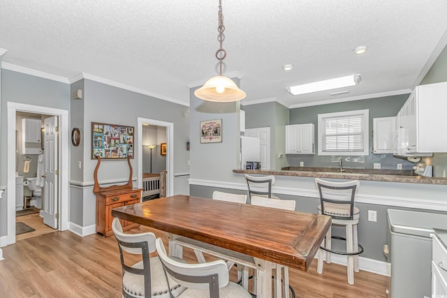 4173 Hibiscus Dr Unit 103, Little River, SC 29566 - dining space featuring light wood-style flooring, a textured ceiling, and crown molding