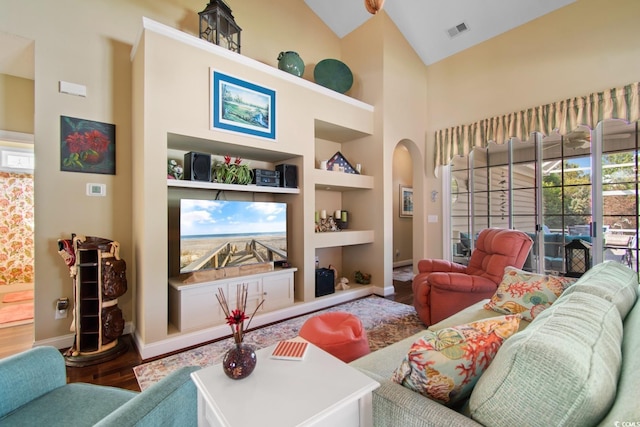5712 Whistling Duck Dr, North Myrtle Beach, SC 29582 - living room featuring high vaulted ceiling, wood finished floors, arched walkways, and built in shelves