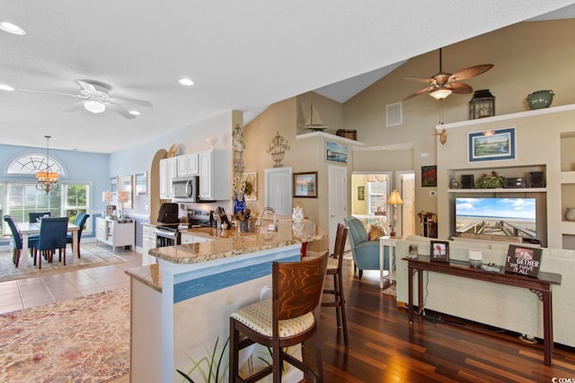 5712 Whistling Duck Dr, North Myrtle Beach, SC 29582 - kitchen with appliances with stainless steel finishes, a ceiling fan, light stone countertops, a kitchen breakfast bar, and white cabinetry