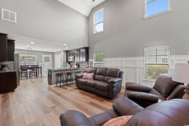 276 Whipple Run Loop, Myrtle Beach, SC 29588 - living room with a towering ceiling, light wood-style floors, a chandelier, and a decorative wall
