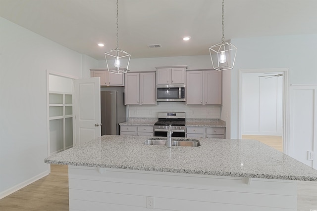 964 Irving Dr, Little River, SC 29566 - kitchen with stainless steel appliances, light wood-type flooring, decorative backsplash, a center island with sink, and gray cabinetry
