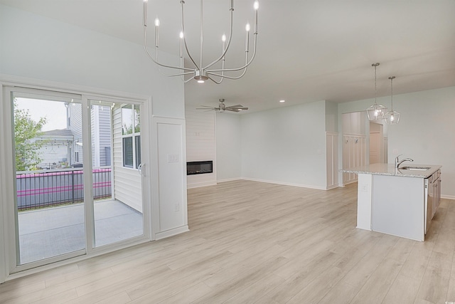 964 Irving Dr, Little River, SC 29566 - kitchen featuring light wood finished floors, light stone counters, a fireplace, a center island with sink, and ceiling fan