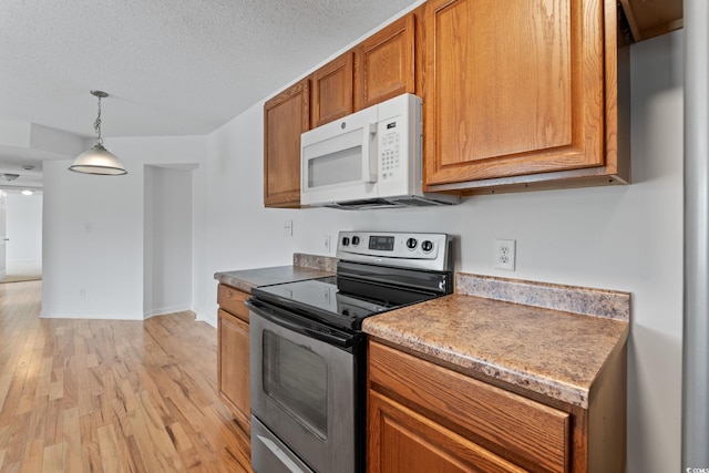 2257 Andover Dr Unit A, Surfside Beach, SC 29575 - kitchen with stainless steel range with electric stovetop, white microwave, light wood-style flooring, brown cabinets, and decorative light fixtures