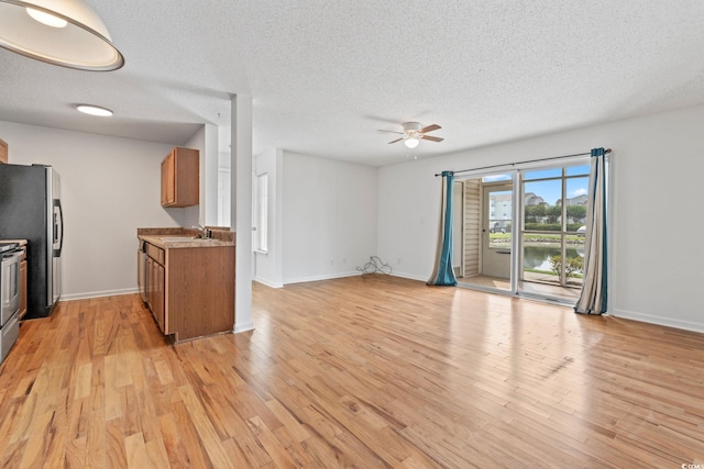 2257 Andover Dr Unit A, Surfside Beach, SC 29575 - unfurnished living room with a ceiling fan, a textured ceiling, light wood-style flooring, and a water view