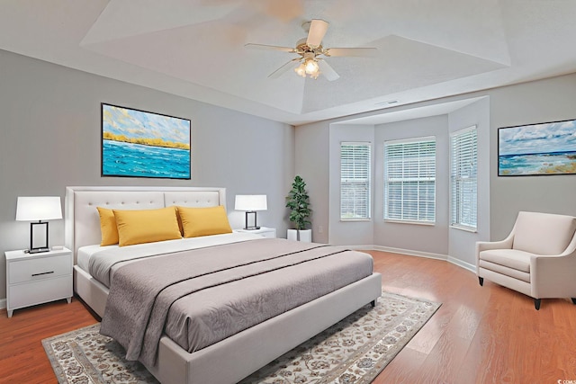 3888 Stillwood Dr, Myrtle Beach, SC 29588 - bedroom with a tray ceiling, light wood-type flooring, and a ceiling fan