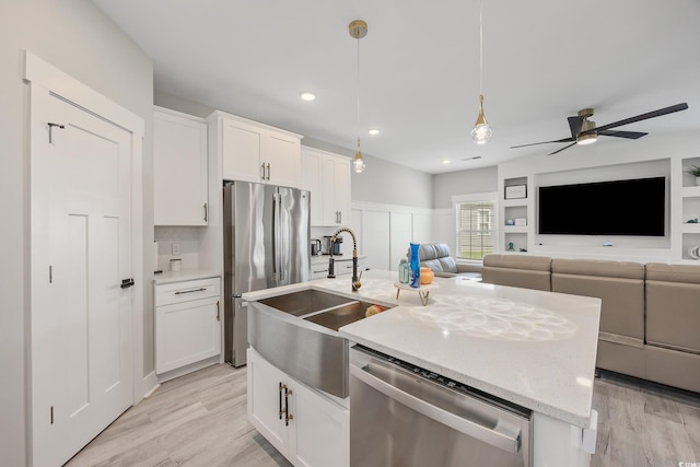 2143 Stonecrest Dr NW, Calabash, NC 28467 - kitchen with appliances with stainless steel finishes, a center island with sink, a ceiling fan, white cabinets, and decorative light fixtures