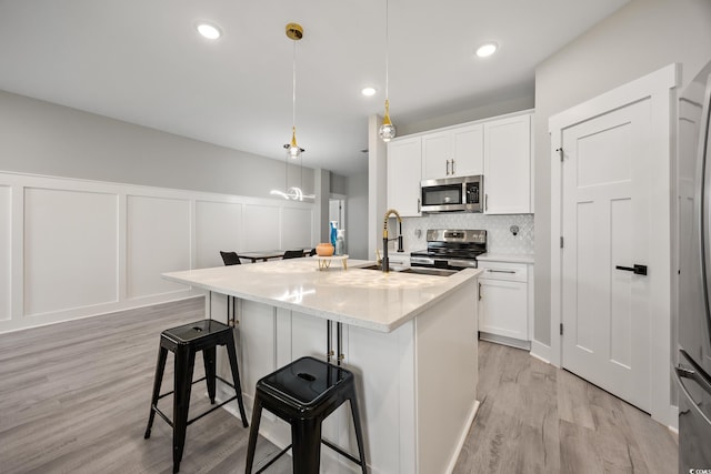 2143 Stonecrest Dr NW, Calabash, NC 28467 - kitchen with stainless steel appliances, light wood-style floors, a breakfast bar area, tasteful backsplash, and white cabinets