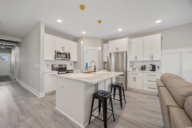 2143 Stonecrest Dr NW, Calabash, NC 28467 - kitchen with appliances with stainless steel finishes, a kitchen breakfast bar, backsplash, light countertops, and light wood-style flooring