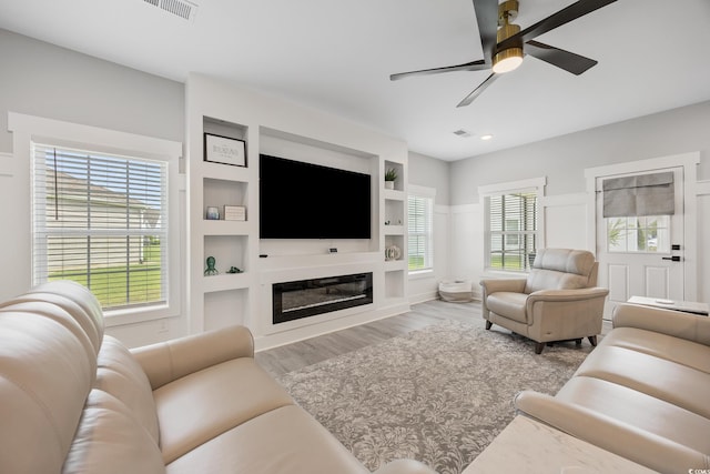 2143 Stonecrest Dr NW, Calabash, NC 28467 - living area featuring a ceiling fan, wood finished floors, built in features, and a glass covered fireplace