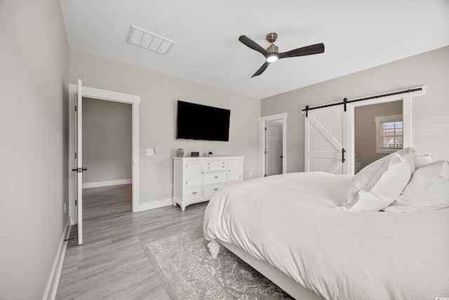 2143 Stonecrest Dr NW, Calabash, NC 28467 - bedroom with a barn door, light wood-style flooring, and ceiling fan